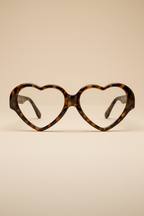 Heart-shaped eyeglasses with tortoiseshell frame on a beige background