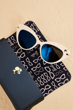 Barbie x Sol Kyst white cat-eye sunglasses with blue lenses, shown with a matching navy case.