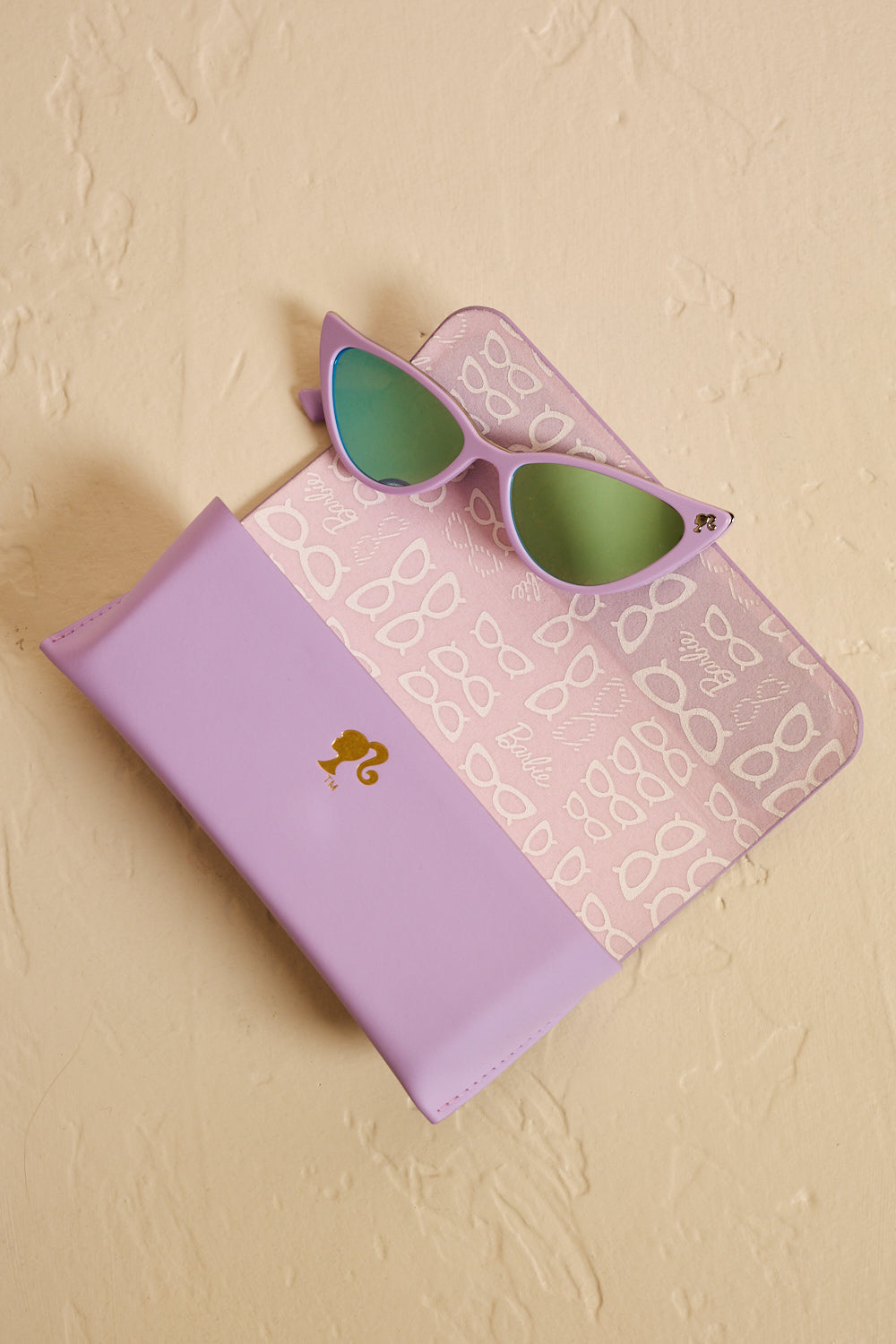Lavender Barbie cat eye sunglasses displayed on an open matching case featuring playful eyewear patterns.