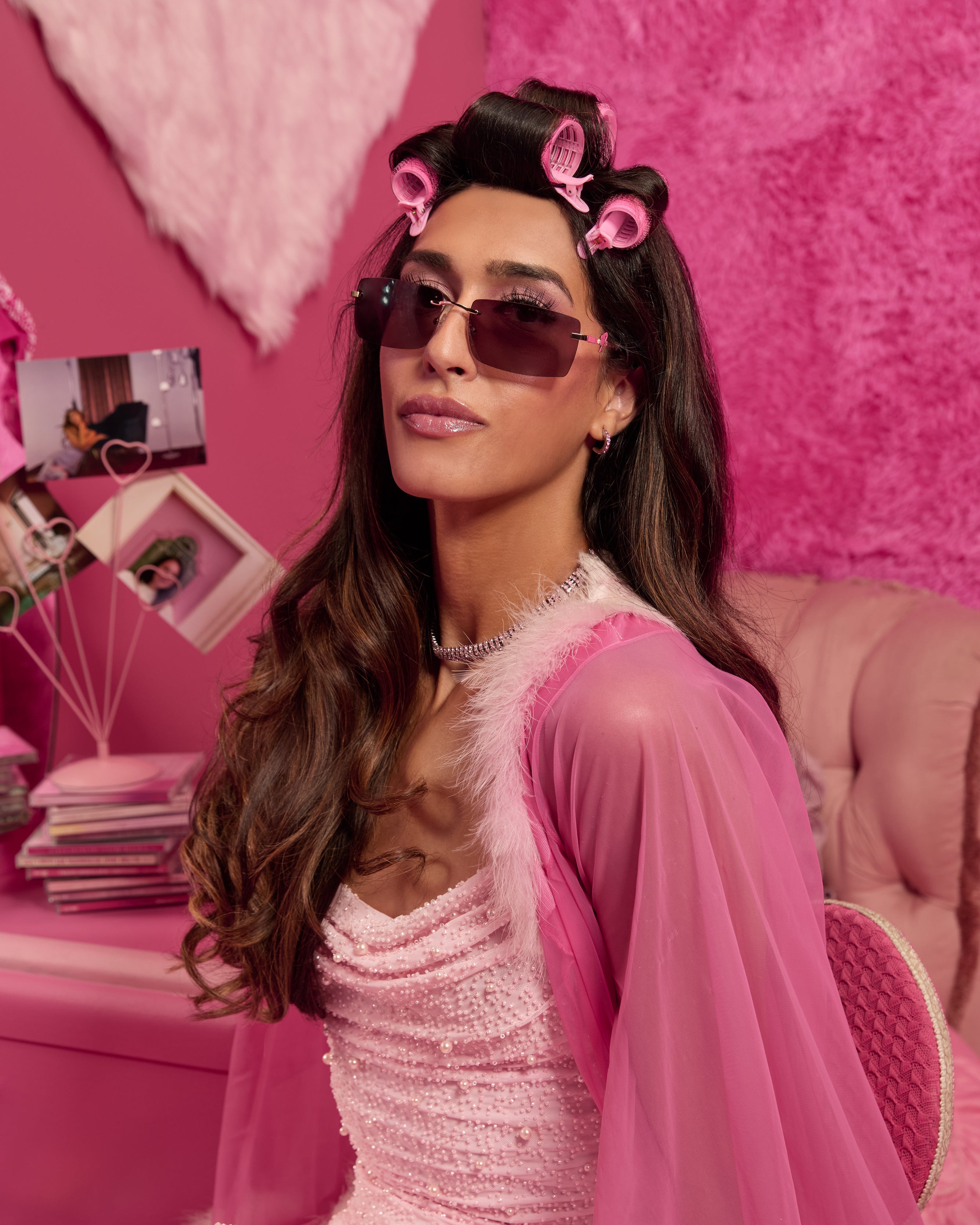 Woman wearing pink Barbie sunglasses, styled in a pink outfit with matching decor.