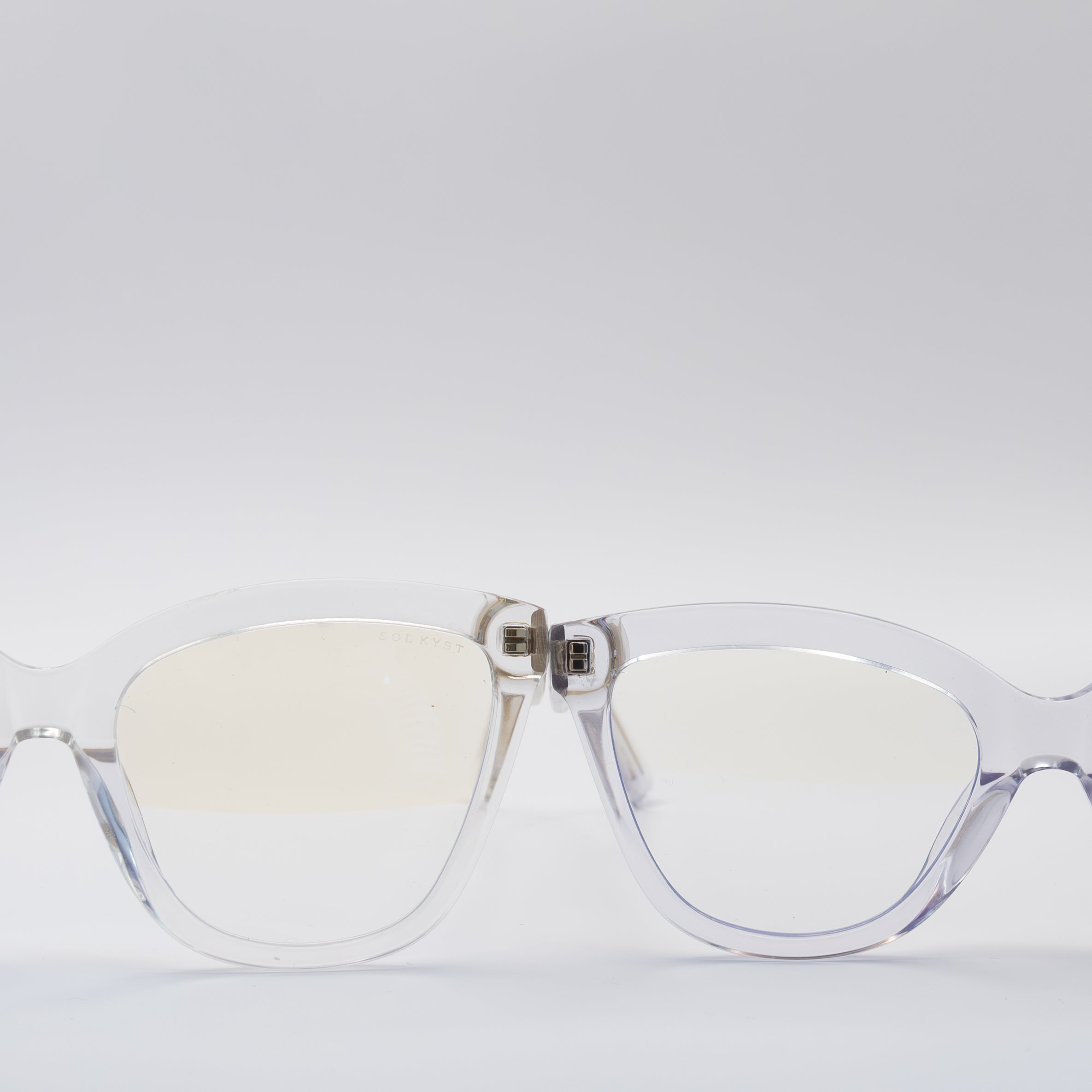 Close-up front view of Sol Kyst Blue Light glasses with clear frames and blue light-blocking lenses, displayed on a white background.