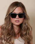 Woman wearing black sunglasses with a neutral background