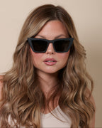 Woman wearing black sunglasses with a neutral background