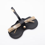 Back view of black Sol Kyst "Kyst Klip" holding beige transparent sunglasses on a white background.