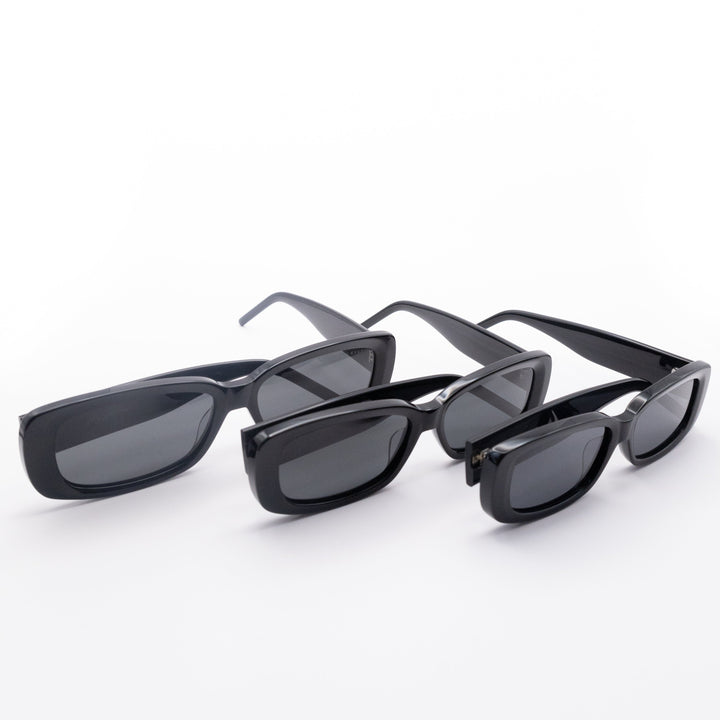 Three Sol Kyst women's rectangle sunglasses with black frames and dark tinted lenses in various sizes in a row.
