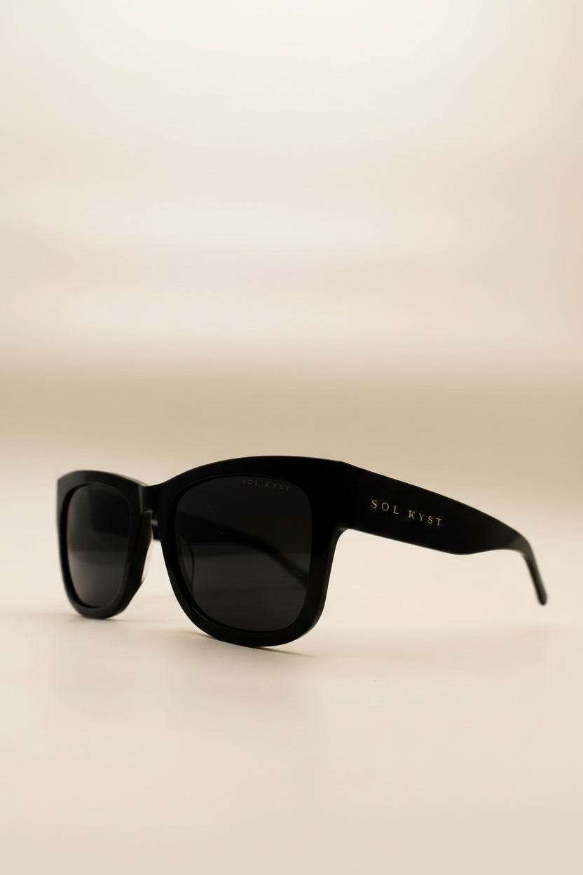 Side view of Sol Kyst women's square sunglasses with black frames and dark tinted lenses.