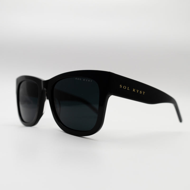 Side view of Sol Kyst women's square sunglasses with black frames and dark tinted lenses.