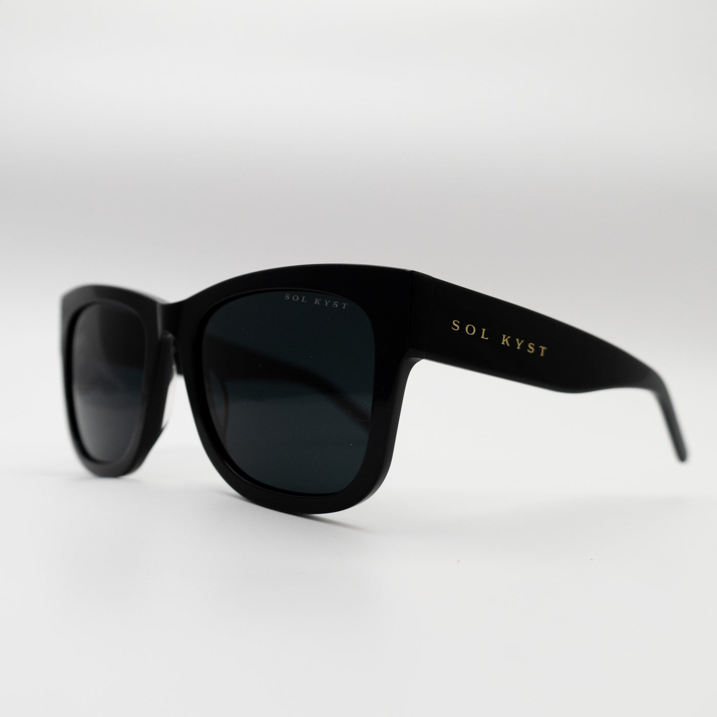 Side view of Sol Kyst women's square sunglasses with black frames and dark tinted lenses.