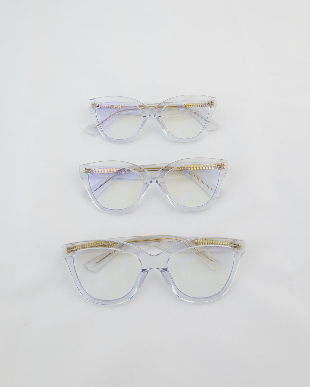 Three women's blue light glasses with clear lenses and clear frames with gold accents.