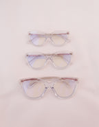 Three women's blue light glasses with clear lenses and clear frames with gold accents.