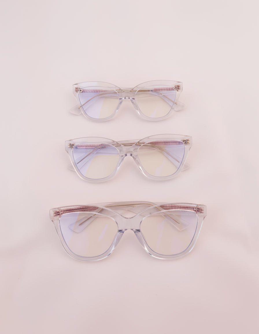 Three women's blue light glasses with clear lenses and clear frames with gold accents.