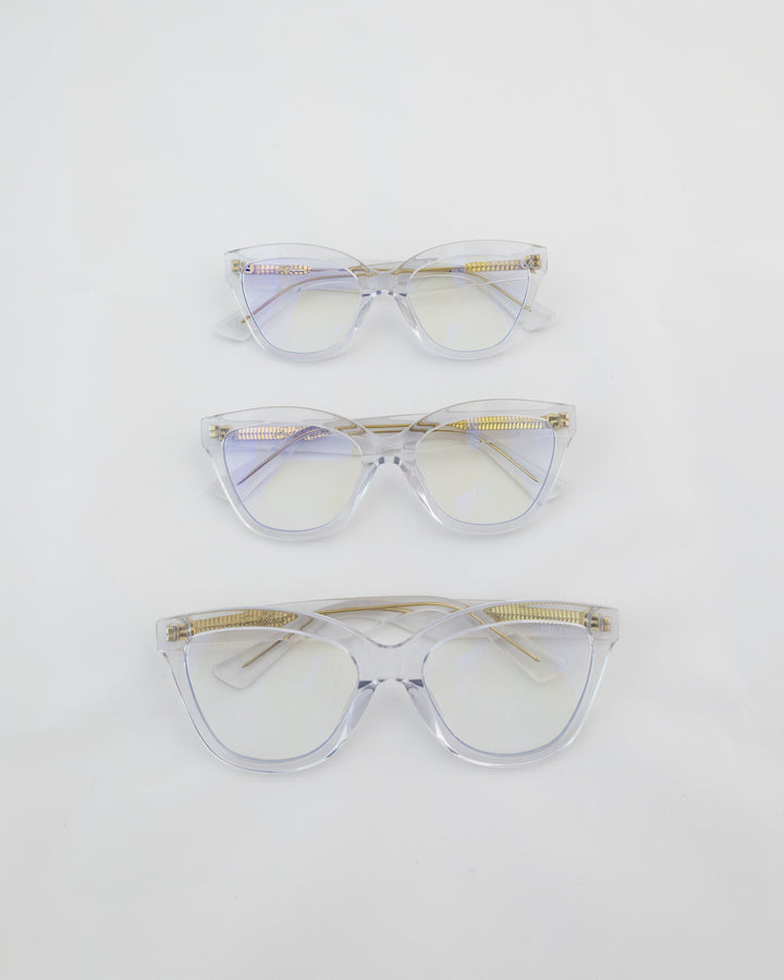 Three women's blue light glasses with clear lenses and clear frames with gold accents.