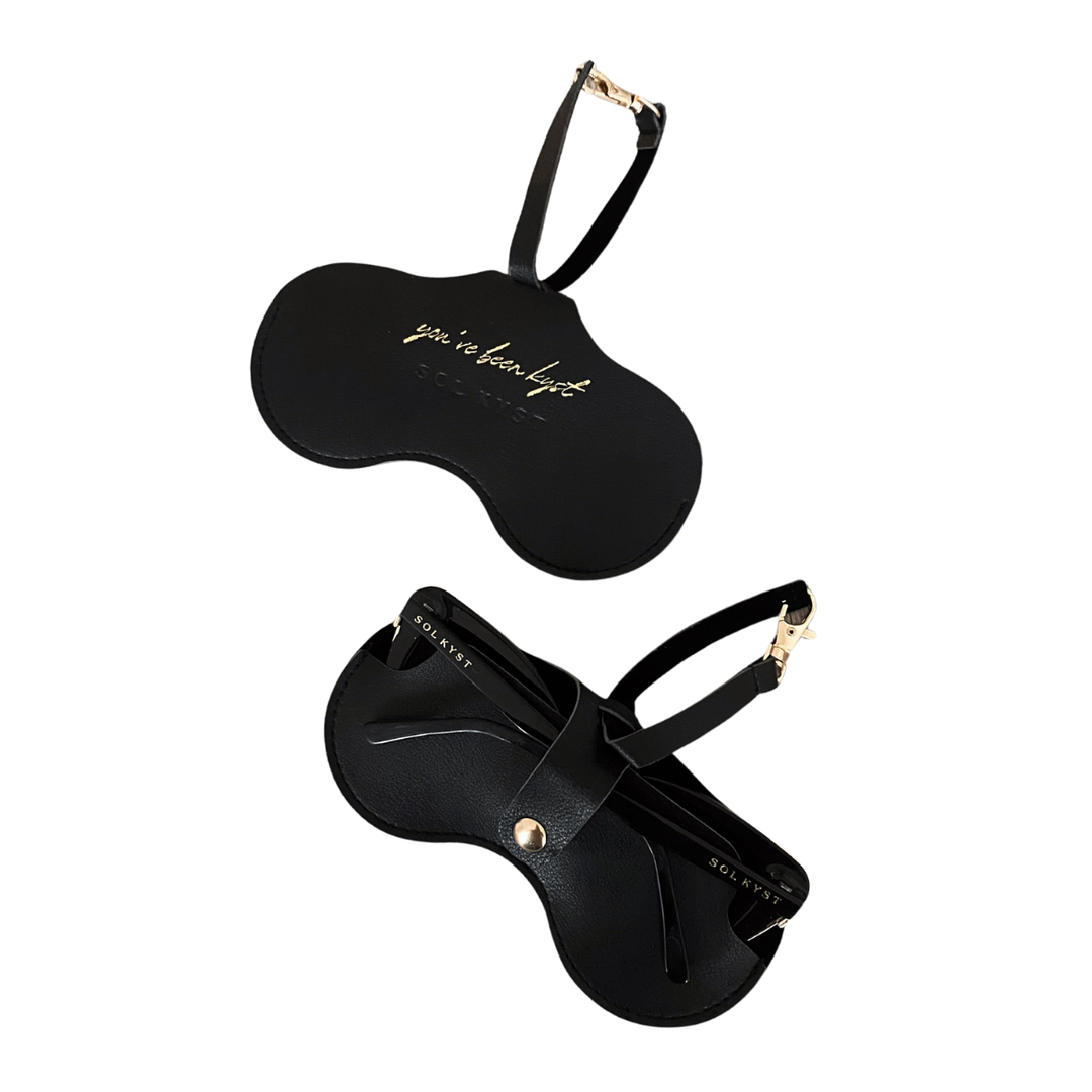 Two views of the black Sol Kyst Kyst Klip, one with 'you’ve been kyst' gold lettering and another holding sunglasses.