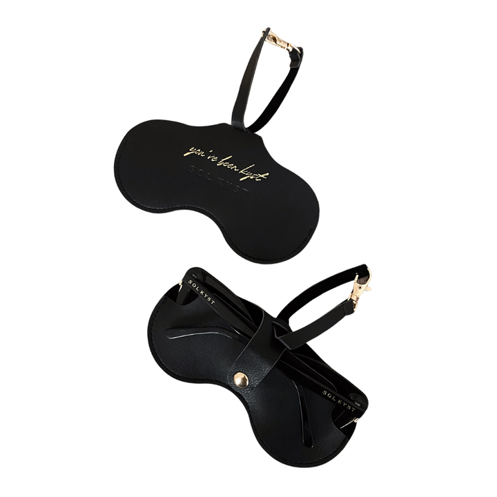 Two views of the black Sol Kyst Kyst Klip, one with 'you’ve been kyst' gold lettering and another holding sunglasses.