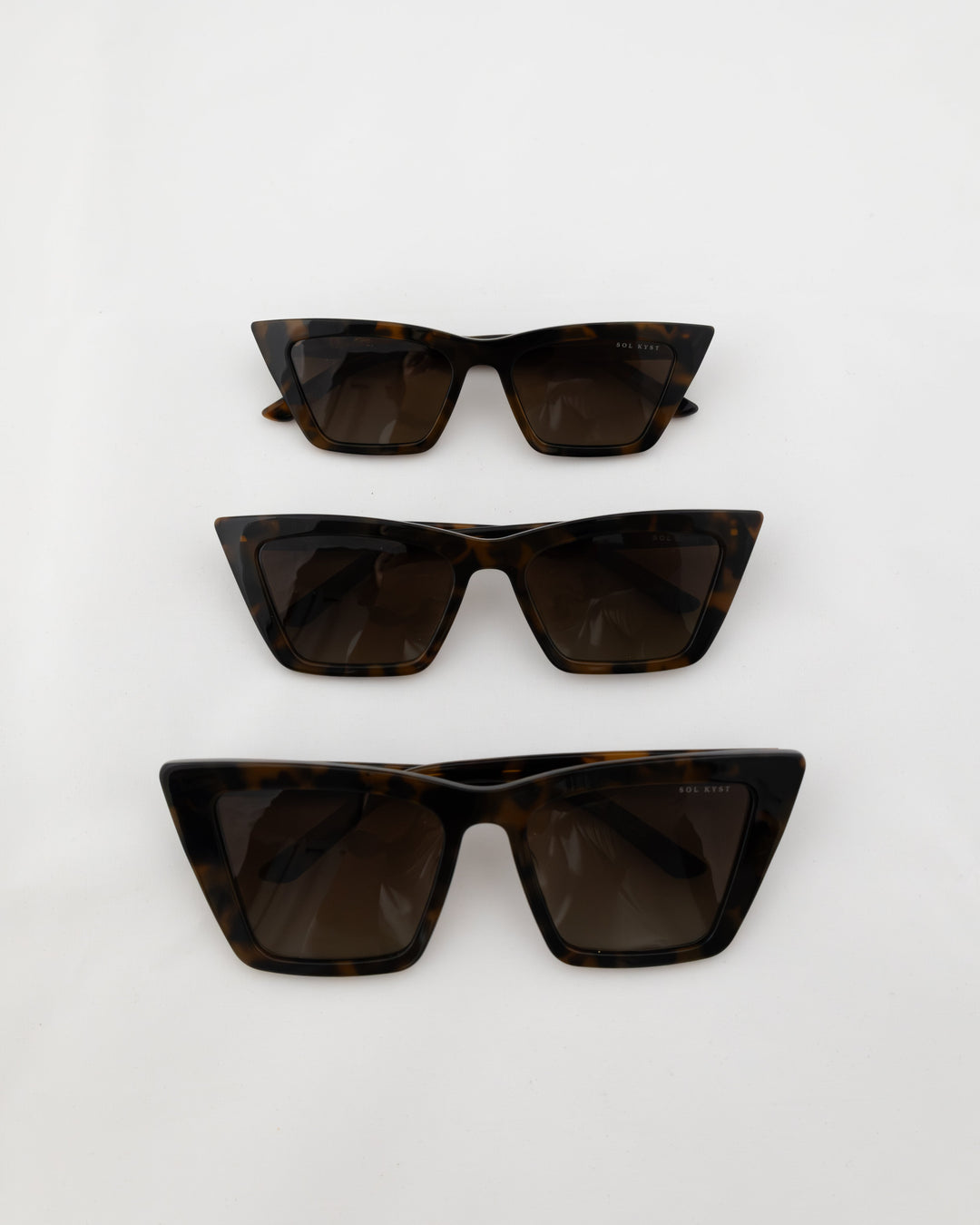 Three pairs of tortoise trapezoid sunglasses with dark lenses displayed in a vertical arrangement on a white background.