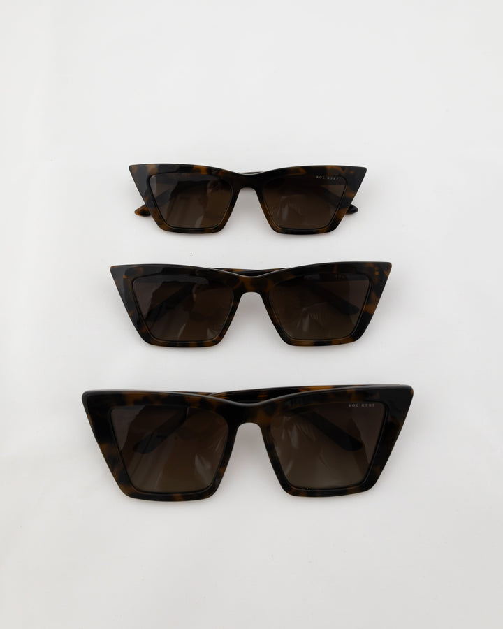 Three pairs of tortoise trapezoid sunglasses with dark lenses displayed in a vertical arrangement on a white background.