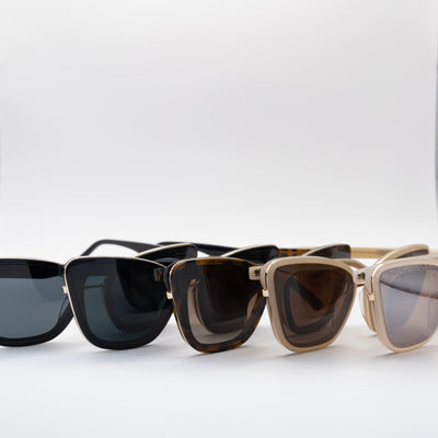 Five pairs of cat eye sunglasses in various colours aligned in a row, on a white background.