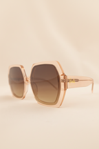 Sunglasses with rose gold frame and brown lenses on a light gray background