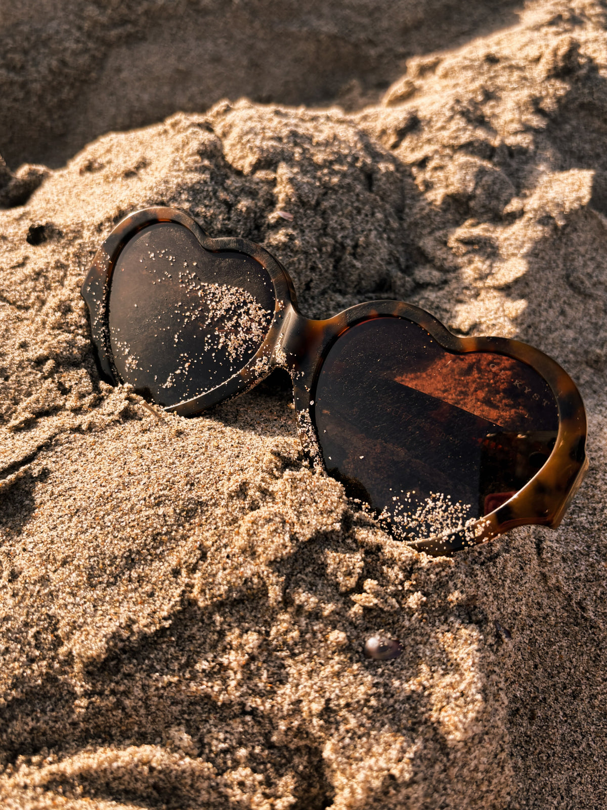 Tortoiseshell heart-shaped sunglasses in the sand
